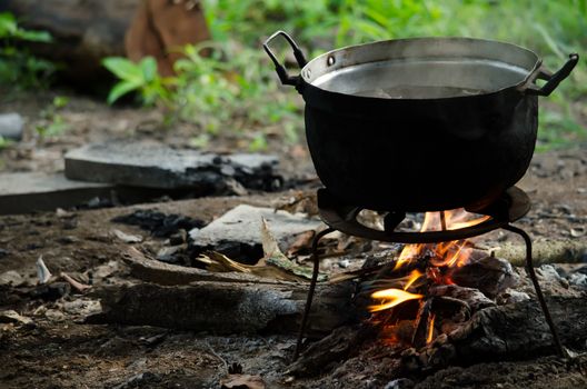 the bonfire is burning firewood under pot