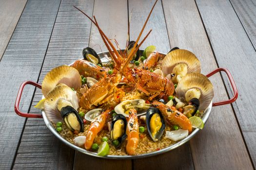 Gourmet seafood Valencia paella with fresh langoustine, clams, mussels and squid on savory saffron rice with prawn, scollops, mussels and lime slices, close up view