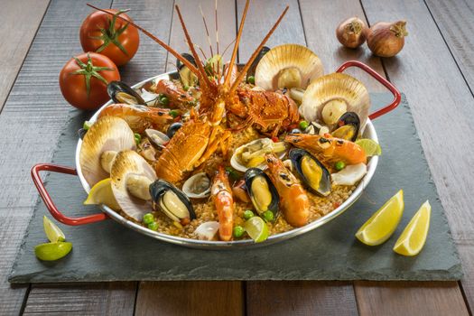Gourmet seafood Valencia paella with fresh langoustine, clams, mussels and squid on savory saffron rice with prawn, scollops, mussels and lime slices, close up view
