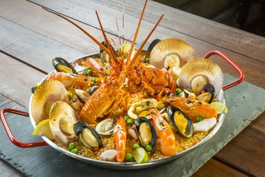 Gourmet seafood Valencia paella with fresh langoustine, clams, mussels and squid on savory saffron rice with prawn, scollops, mussels and lime slices, close up view