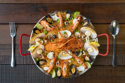 Gourmet seafood Valencia paella with fresh langoustine, clams, mussels and squid on savory saffron rice with prawn, scollops, mussels and lime slices, close up view