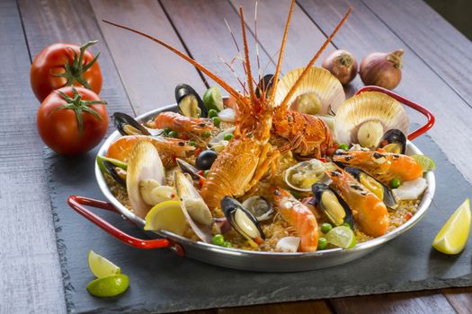 Gourmet seafood Valencia paella with fresh langoustine, clams, mussels and squid on savory saffron rice with prawn, scollops, mussels and lime slices, close up view