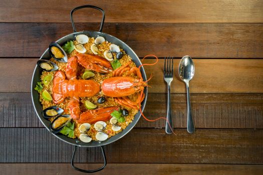 Gourmet seafood Valencia paella with fresh langoustine, clams, mussels and squid on savory saffron rice with peas and lemon slices, above view