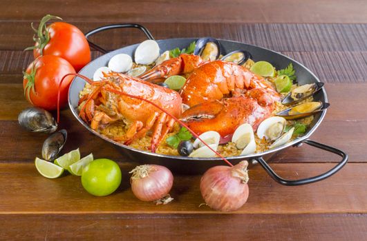 Gourmet seafood Valencia paella with fresh langoustine, clams, mussels and squid on savory saffron rice with peas and lemon slices, close up view