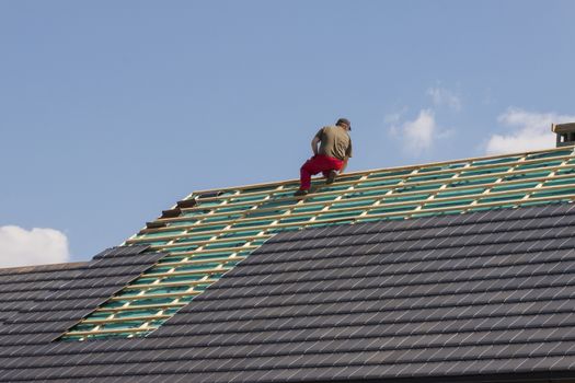 Roofer working on the top of the unfinished roof