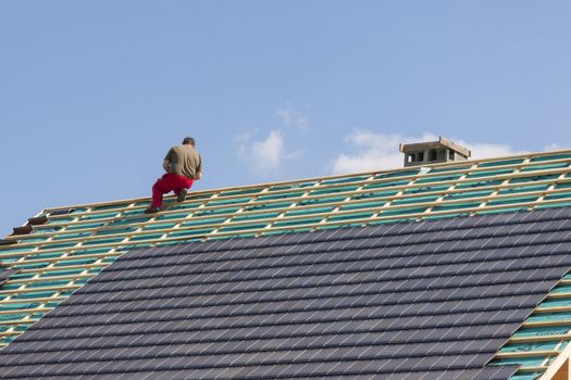 Roofer working on the top of the unfinished roof