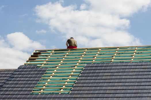 Roofer working on the top of the unfinished roof