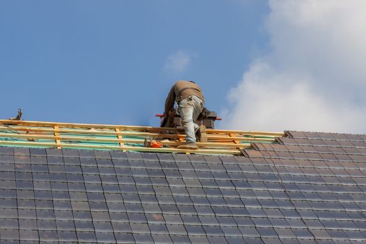 Roofer working on the top of the unfinished roof