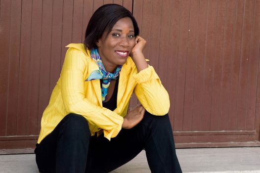 This young woman sitting hand under chin, smiling seems to be tired.