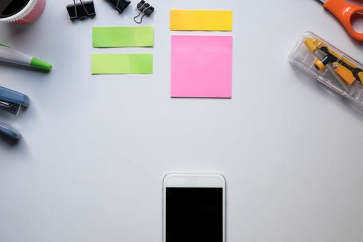 Top view of copy space of white working table work space with notebook, cup,note paper,pencil,clip,smartphone and other supplies.