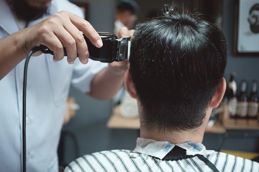 Hairdresser makes hairstyle a man with vintage tone.