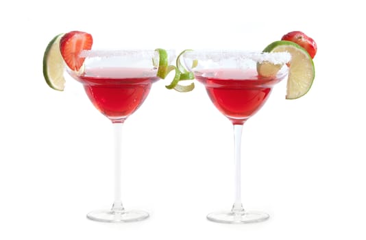 Two cocktail glasses with lime and strawberry slices over a white background