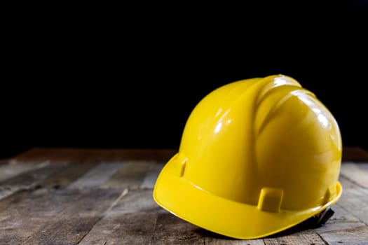 Yellow helmet on an old wooden table. Workshop in the workshop. Wooden table, black background.