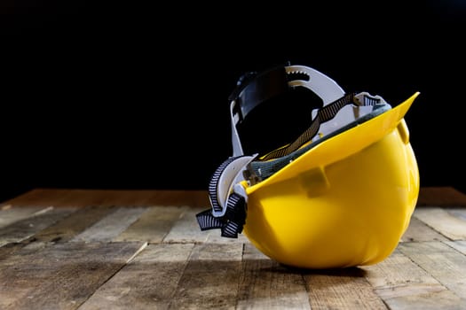 Yellow helmet on an old wooden table. Workshop in the workshop. Wooden table, black background.