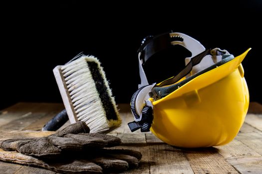 Yellow helmet and carpenter tools. Carpenter and old wooden table. Black background