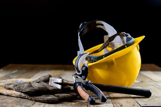 Yellow helmet and carpenter tools. Carpenter and old wooden table. Black background