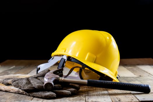 Yellow helmet and carpenter tools. Carpenter and old wooden table. Black background