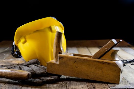 Yellow helmet and carpenter tools. Carpenter and old wooden table. Black background