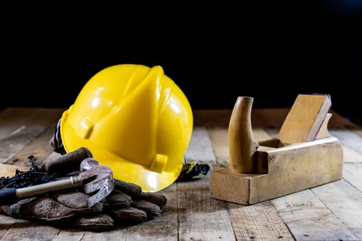 Yellow helmet and carpenter tools. Carpenter and old wooden table. Black background