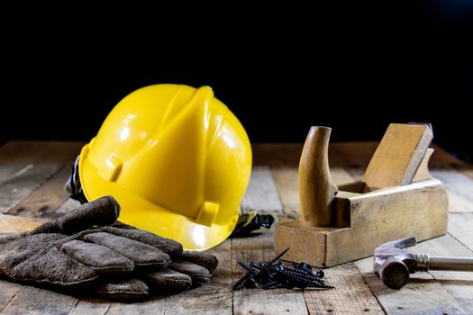 Yellow helmet and carpenter tools. Carpenter and old wooden table. Black background