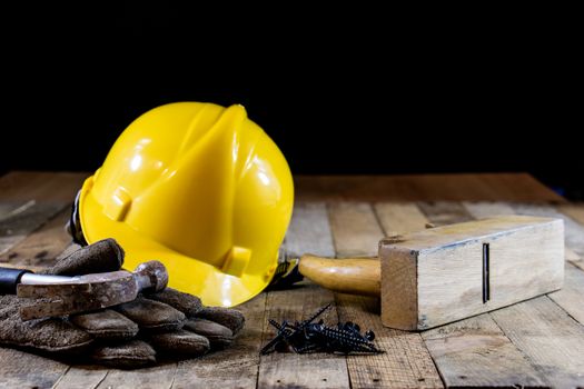 Yellow helmet and carpenter tools. Carpenter and old wooden table. Black background