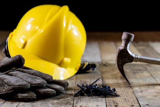 Yellow helmet and carpenter tools. Carpenter and old wooden table. Black background