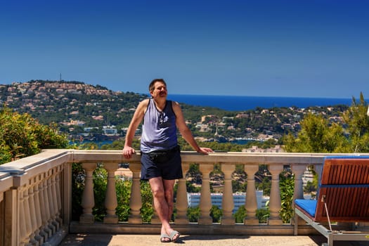 Man is relaxing on a balcony overlooking the sea.