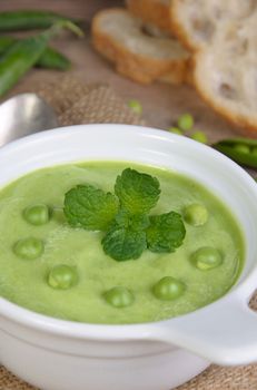 A plate of soup puree of green peas with mint  on a table