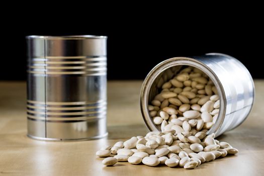 Delicious beans in a metal jar on a wooden kitchen table. Black background.