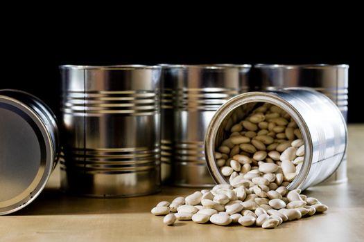 Delicious beans in a metal jar on a wooden kitchen table. Black background.