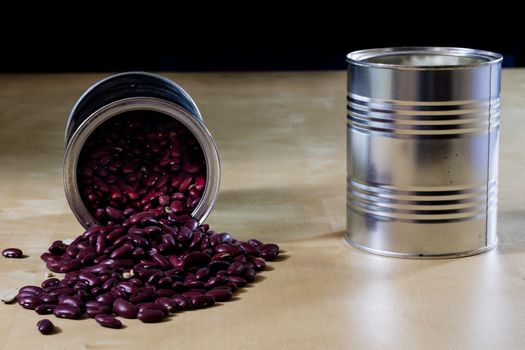 Delicious beans in a metal jar on a wooden kitchen table. Black background.