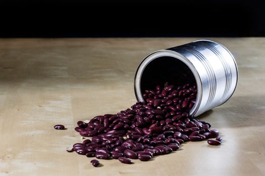 Delicious beans in a metal jar on a wooden kitchen table. Black background.