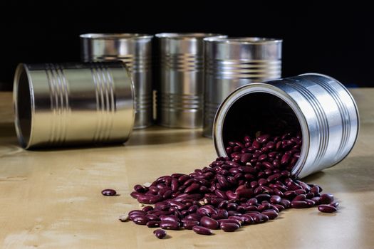 Delicious beans in a metal jar on a wooden kitchen table. Black background.