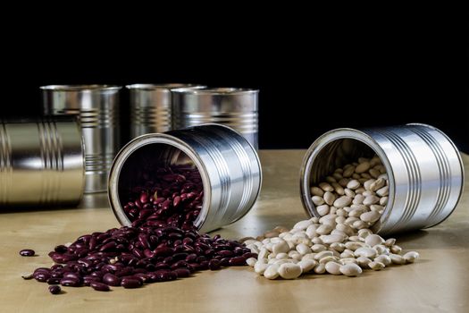 Delicious beans in a metal jar on a wooden kitchen table. Black background.