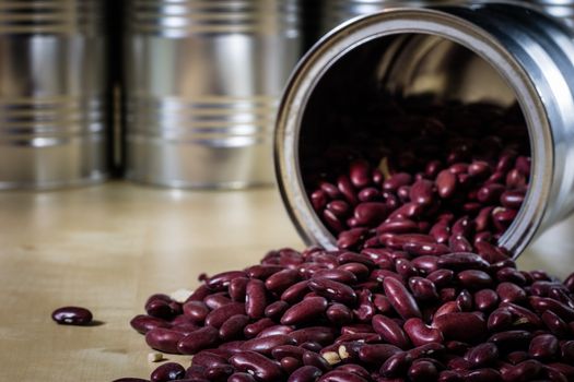 Delicious beans in a metal jar on a wooden kitchen table. Black background.