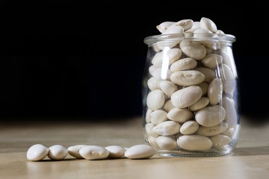 Delicious bean in a glass jar on a wooden kitchen table. Black background.