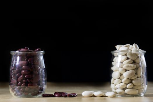 Delicious bean in a glass jar on a wooden kitchen table. Black background.