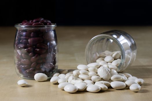 Delicious bean in a glass jar on a wooden kitchen table. Black background.
