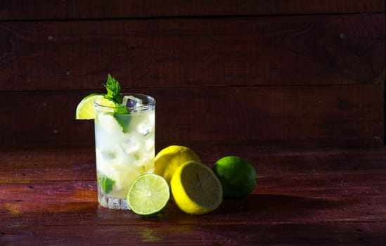 A glass of lemonade with lemon slices, lime, mint and ice
