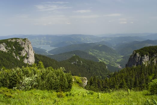 Summer landscape from the top of mountains, green pasture and forest in valley.