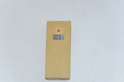 Thermometer on a white exterior wall shows 30 degrees. Concept hot summer day.