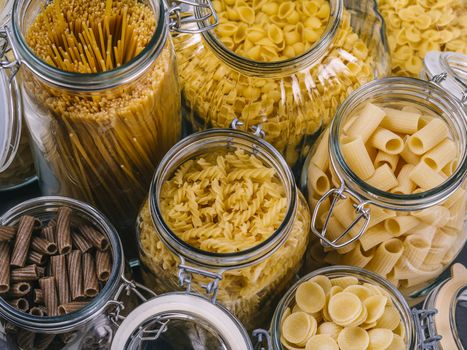 Photo of different pasta types in large glass jars.