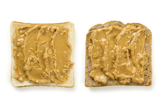 Photo of two slices of white and whole wheat bread covered in peanut butter, isolated on white.