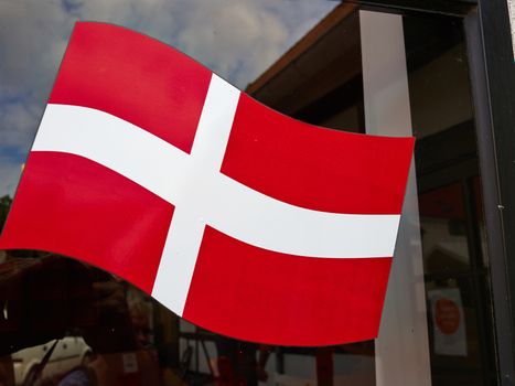 Flag of Denmark up high on a glass window of a house