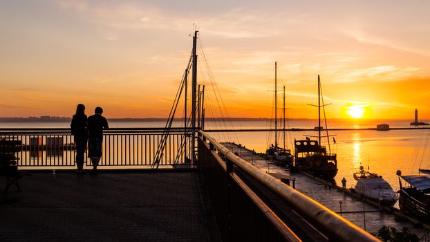 Romantic couple meets the dawn in the seaport