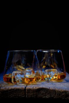 Glass of scotch whiskey and ice isolated on wooden table