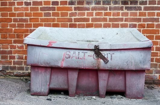 an old and retro looking red salt grit locked container outside; UK