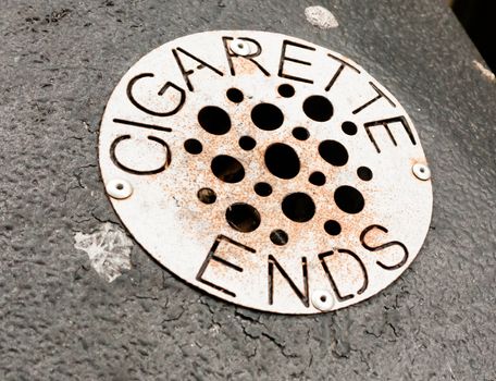 close up of metal grate with holes on bin for cigarette ends; UK