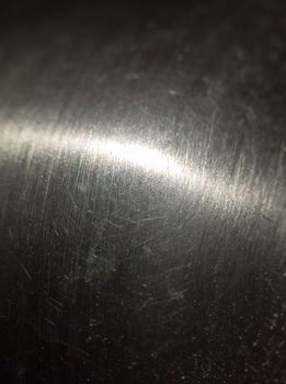 close up scratched metal surface with light across; UK