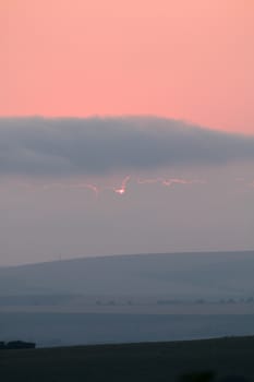 Sun just about to disappear behind cloud at sunset from Seaford, East Sussex looking across towards Beddingham Hill.